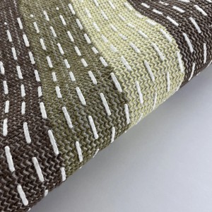 Dettaglio di un tappeto da bagno a righe marroni e beige con cuciture decorative bianche.