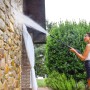 Donna pulisce muro in pietra con idropulitrice t.b.t. all'aperto.