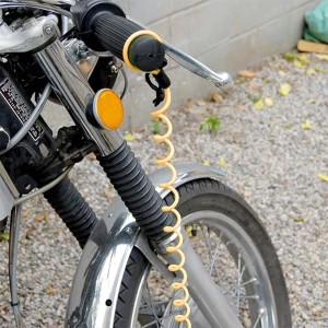 Lucchetto a cavo a spirale giallo fissato al manubrio della moto.