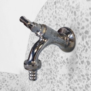 Primo piano di un rubinetto cromato su una fontana da giardino.