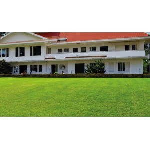 Superficie di erba sintetica t.b.t. verde davanti a un edificio bianco con tetto rosso.