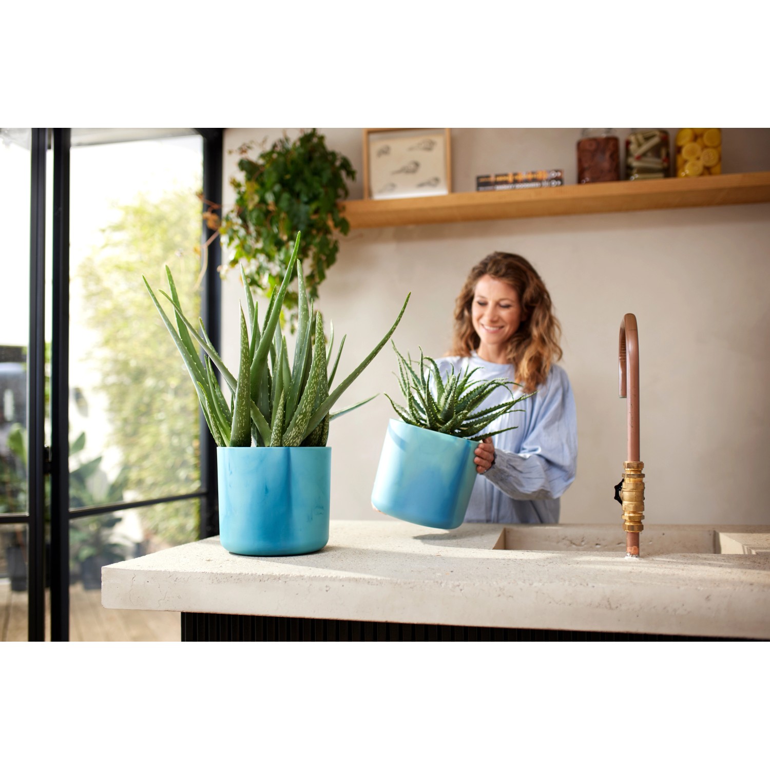 Vasi da fiori Elho Ocean Collection, Ø 16 cm, blu Atlantico, con piante su un bancone da cucina.