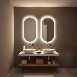 Due specchi da parete ovali illuminati a LED sopra un doppio lavabo in un bagno moderno.