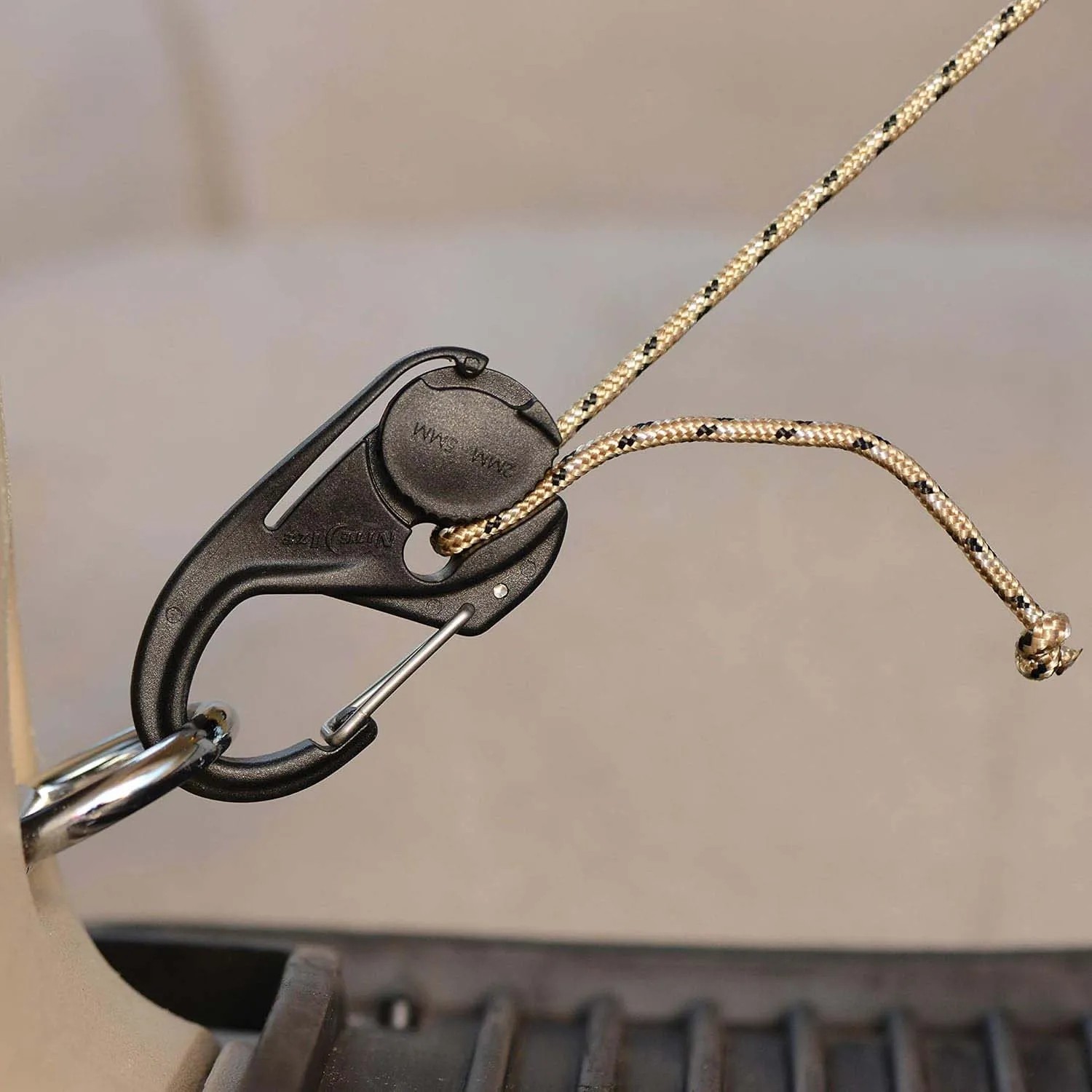 Tenditore per fune t.b.t. nero con corda beige e anello metallico.