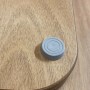 Dettaglio di un accessorio doccia grigio su una superficie di legno.