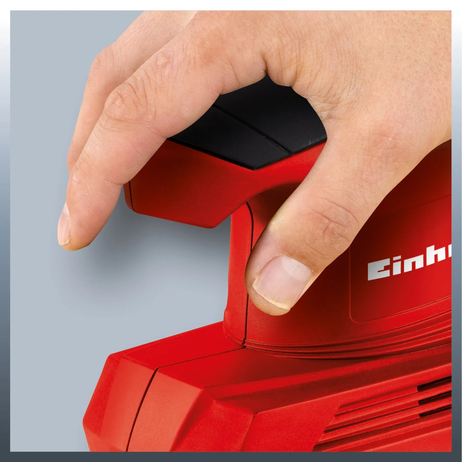Levigatrice orbitale Einhell TC-OS 1520 in uso, levigatrice rossa con mano sull'interruttore.