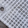 Dettaglio di un telo di copertura trasparente con occhiello e struttura a griglia.