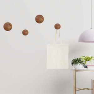 Appendiabiti a parete t.b.t. con quattro ganci rotondi effetto vimini, uno con borsa di stoffa.