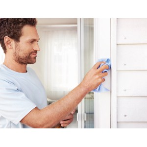 Uomo pulisce telaio bianco della porta con panno blu. Adatto per l'installazione della tenda magnetica Tesa.