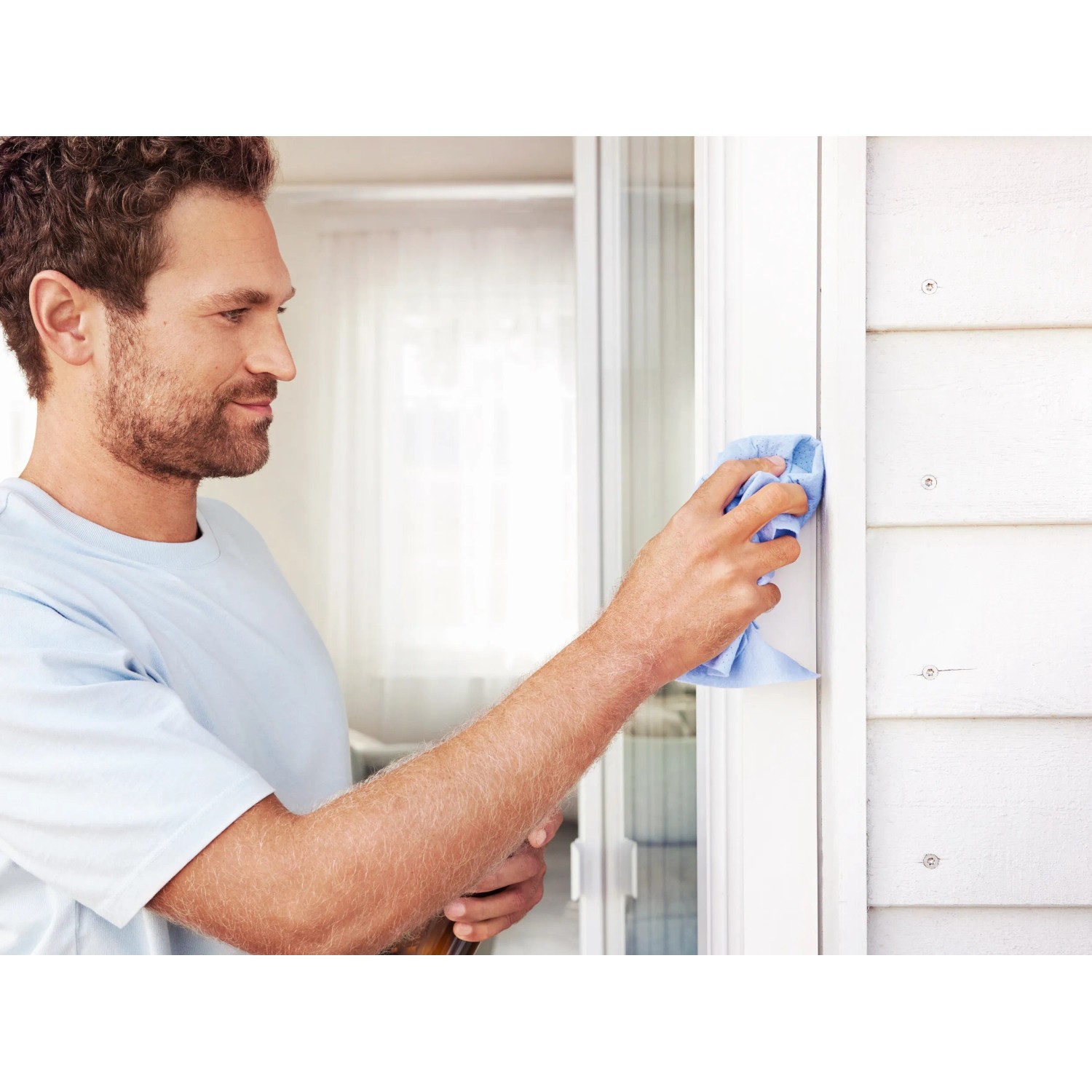Uomo pulisce telaio bianco della porta con panno blu. Adatto per l'installazione della tenda magnetica Tesa.
