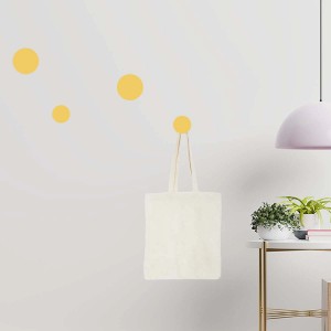 Appendiabiti t.b.t. con borsa di stoffa su parete con punti decorativi gialli.