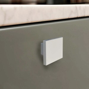 Pomello per mobile quadrato bianco su cassetto grigio. Ideale per mobili moderni.
