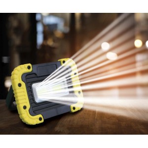 Faro da cantiere a LED t.b.t. con cornice gialla e fascio di luce brillante.