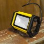 Faro LED da esterno giallo su un banco da lavoro. Proiettore compatto per uso esterno.