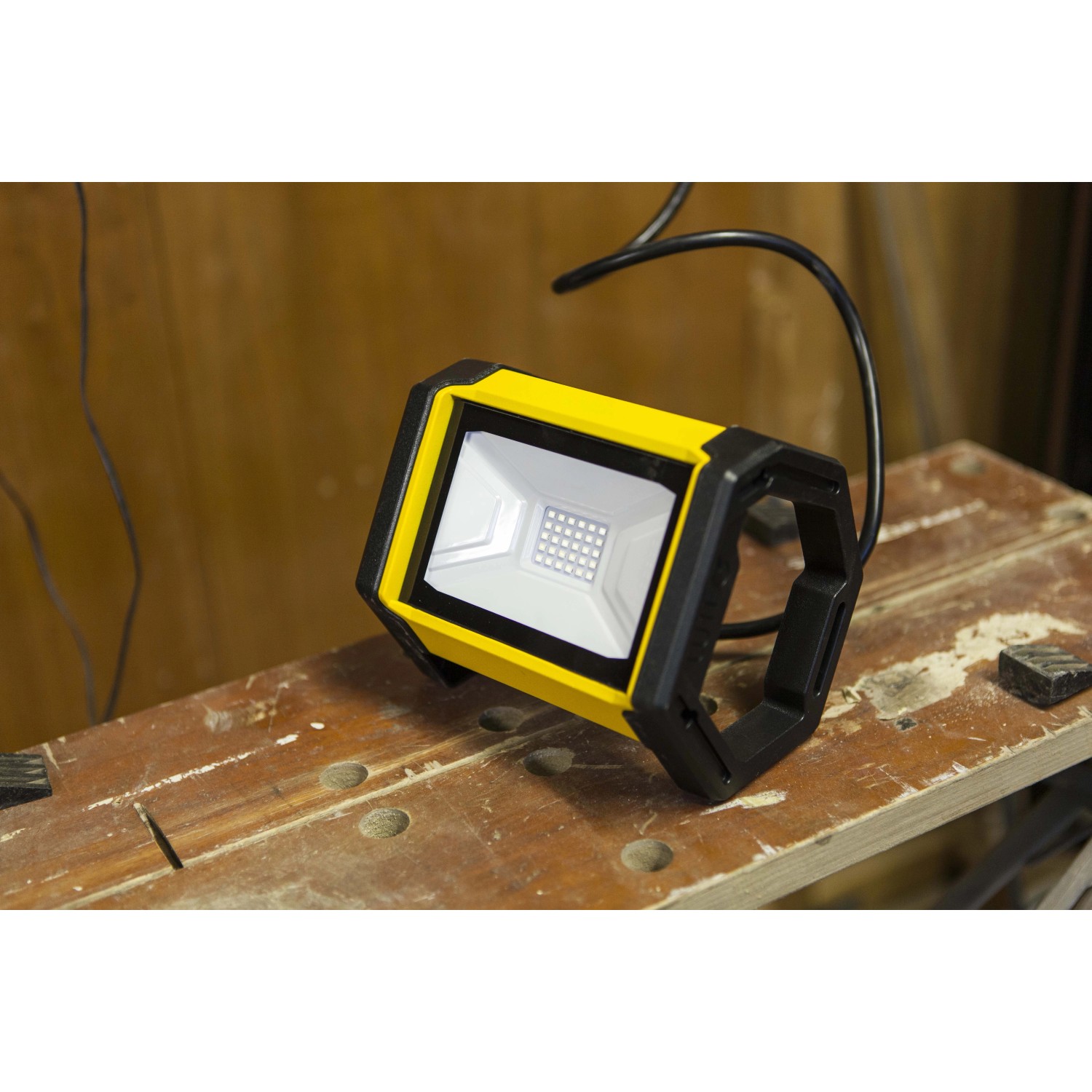 Faro LED da esterno giallo su un banco da lavoro. Proiettore compatto per uso esterno.