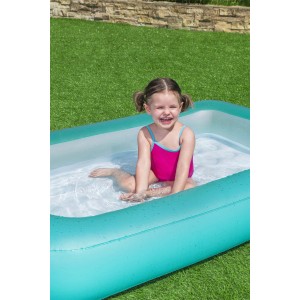 Bambina felice nella piscina per bambini. Piscina rettangolare turchese e bianca.