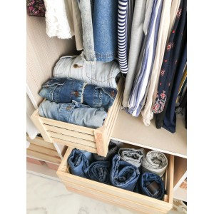 Cassettiera aperta in legno nell'armadio con vestiti piegati.