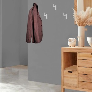Giacca su ganci a muro accanto a comò in legno. Organizer armadio per riporre con stile.