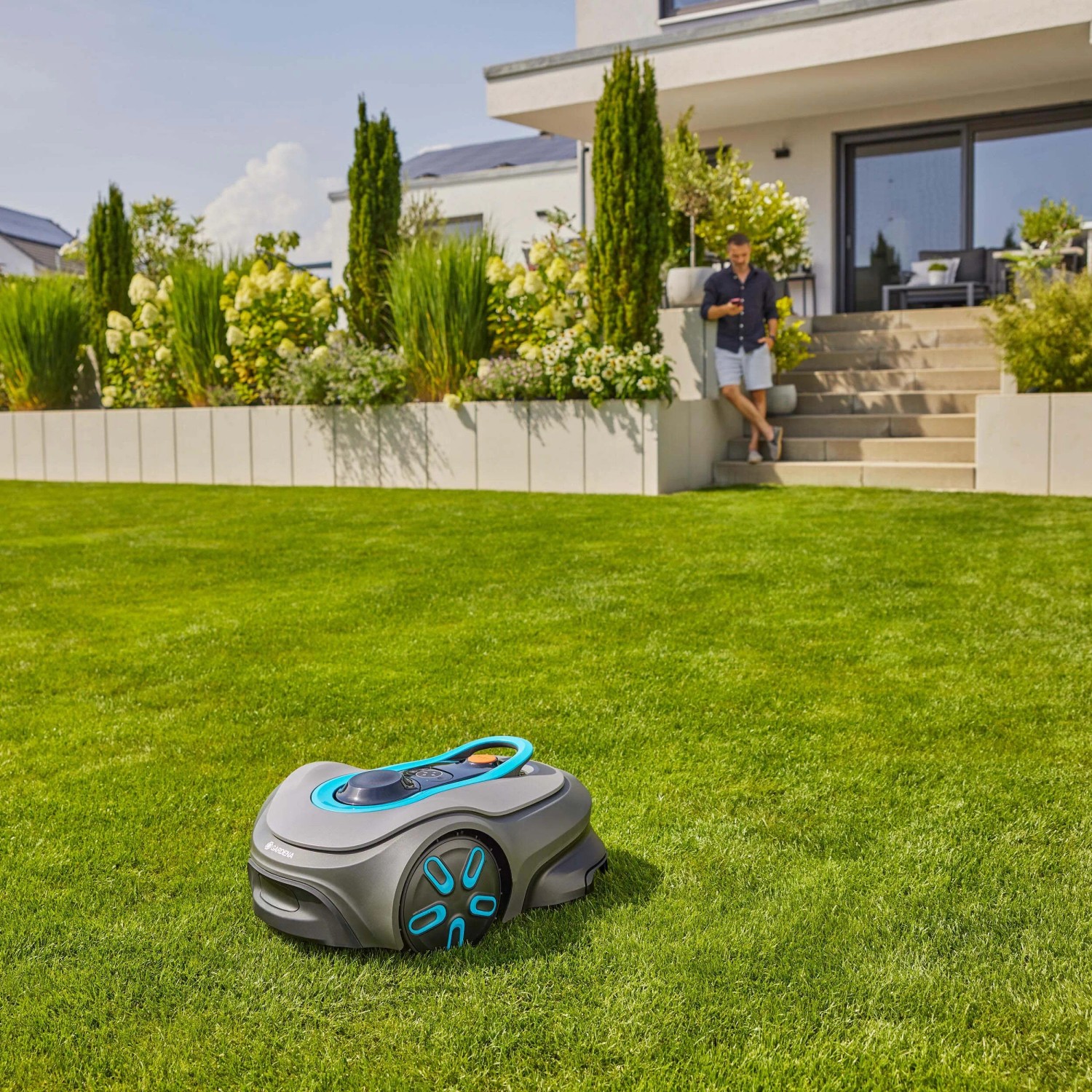 Robot tagliaerba t.b.t. grigio su prato davanti casa. Cura automatica del prato.
