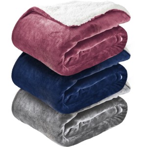 Coperte/plaid t.b.t. impilate in rosa, blu e grigio con fodera bianca.