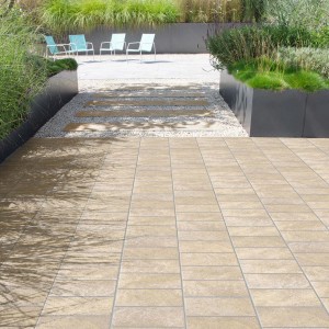Piastrelle per pavimenti beige su un patio con vegetazione sullo sfondo.