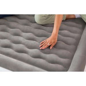 Materasso gonfiabile grigio da campeggio con una mano che tocca la superficie.