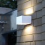 Lampada da parete per esterni a LED LUTEC Gemini bianca su muro di mattoni, che emette luce verso l'alto e verso il basso.