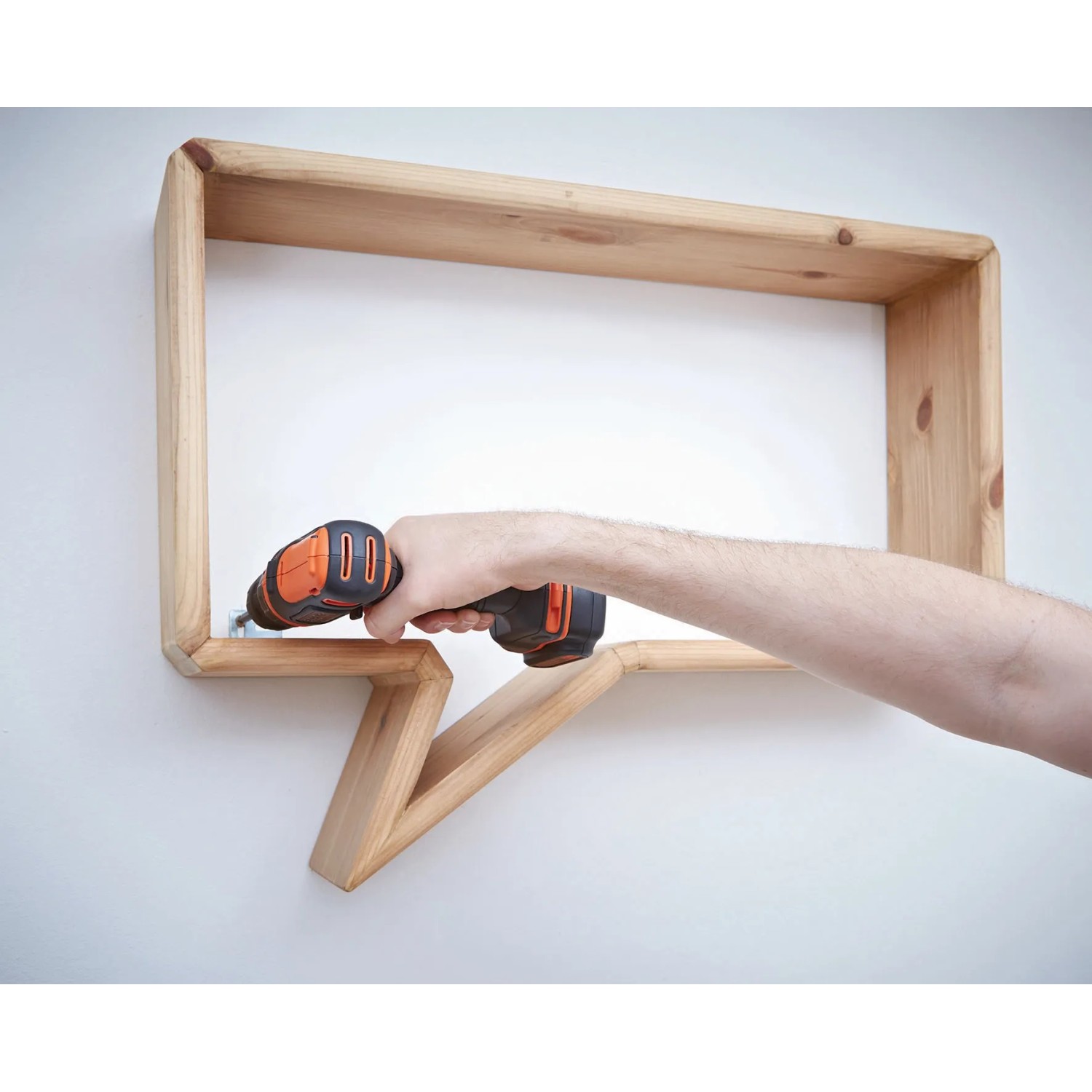 Avvitatore a batteria Black+Decker BDCDD12K che avvita una mensola di legno.