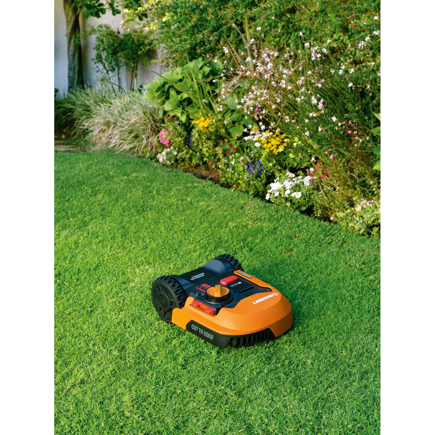 Robot rasaerba Worx Landroid M500 su erba davanti all'aiuola. Robot tagliaerba con batteria da 20 V.
