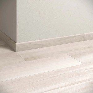 Piastrelle per pavimenti chiare e battiscopa coordinati posati nella stanza.