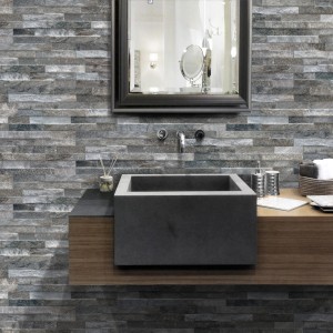 Bagno con piastrelle da rivestimento effetto pietra, lavabo e specchio.