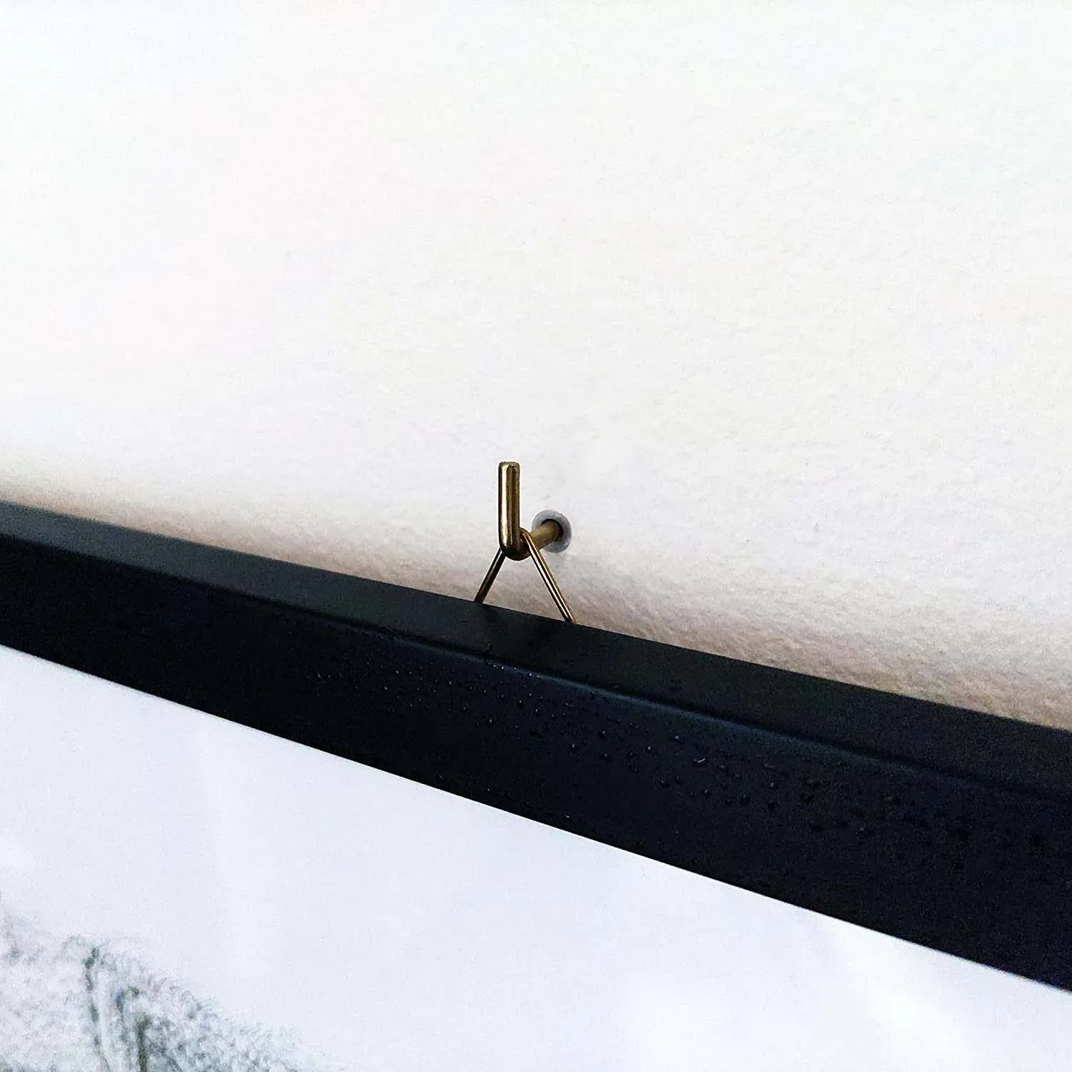 Primo piano di un appendiabiti Tasselli su una parete con un quadro incorniciato.