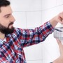 Uomo che monta il cestello doccia Tesa Aluxx (25 cm, cromato) sulla parete del bagno.