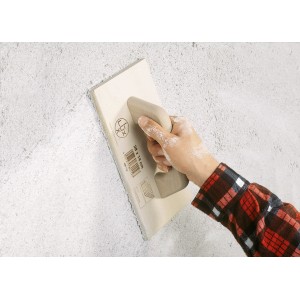 Mano che usa la spatola LUX per lisciare un muro. Strumento da muratore con manico.
