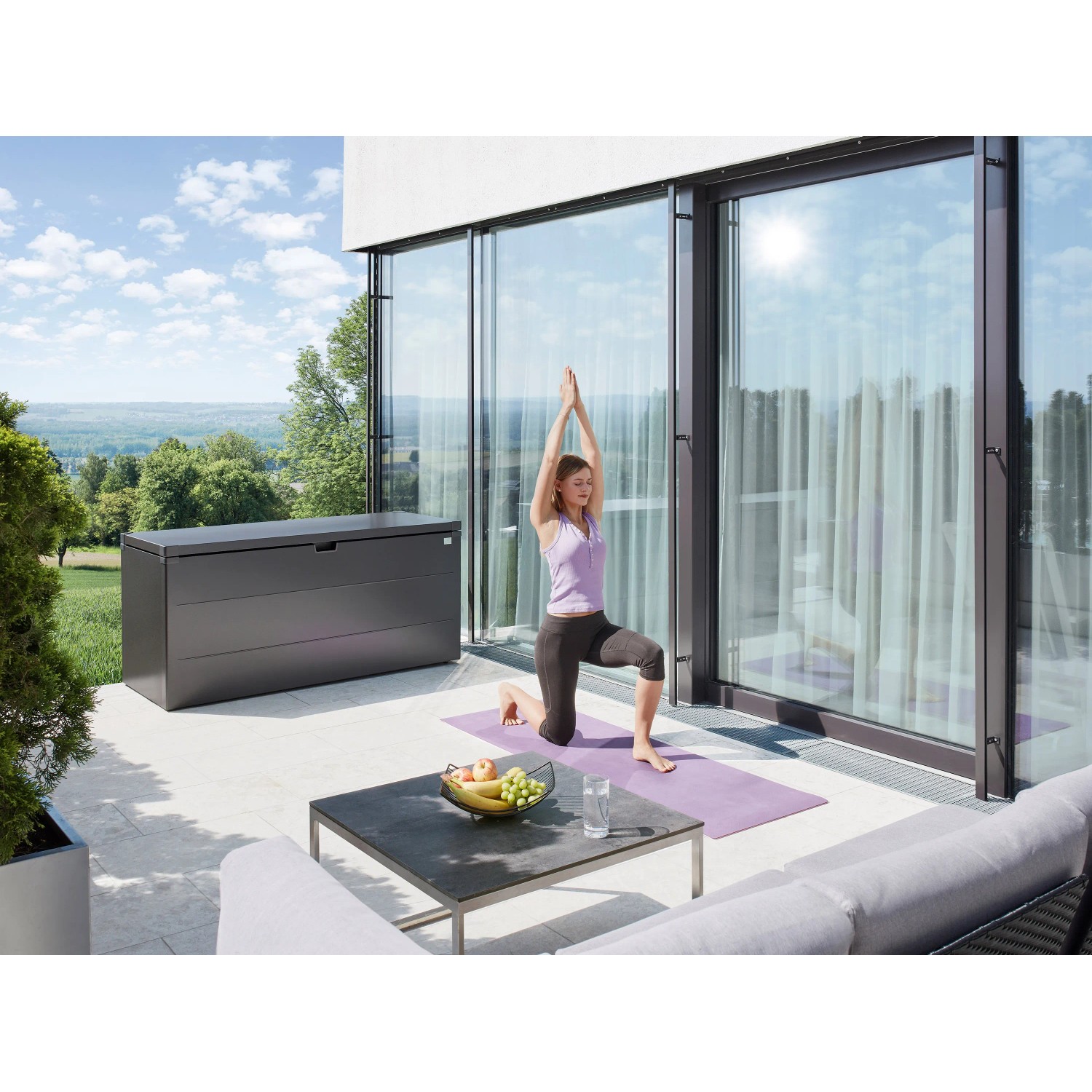 Biohort Stylebox 170 in grigio scuro metallizzato su terrazza con donna che fa yoga.