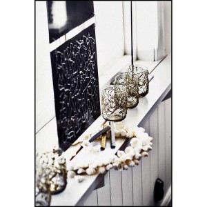 Composizione decorativa con portacandele, ghirlanda di conchiglie e arte murale astratta.