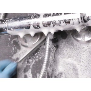 Pulizia di un rubinetto con schiuma e un utensile. Utensile da cucina per la pulizia.