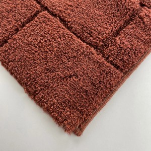 Dettaglio di un tappeto da bagno t.b.t. marrone e soffice con motivo quadrato.