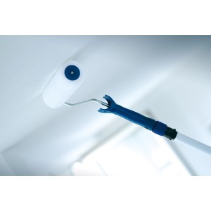 Rullo LUX Vestan con asta telescopica (25 cm) mentre dipinge un soffitto.