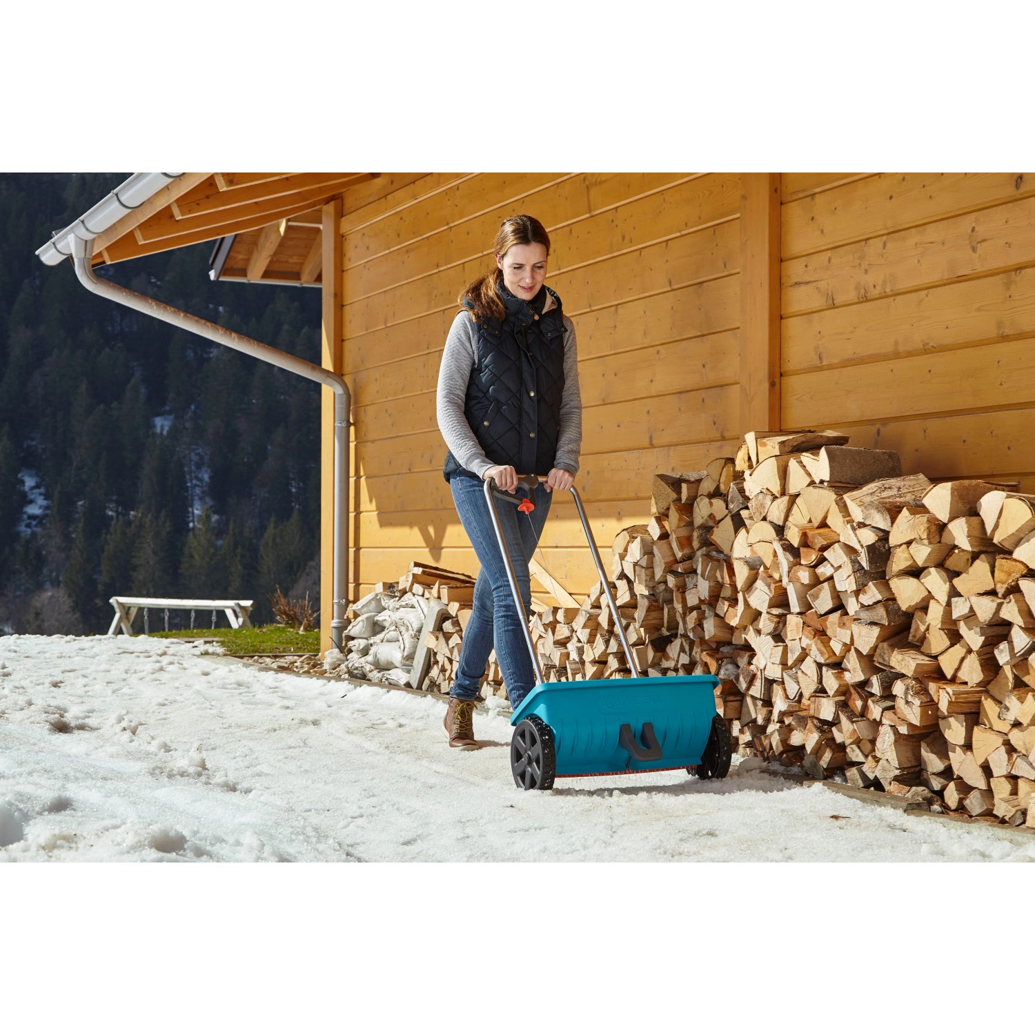 Donna che usa lo spargitore Gardena L per spargere materiale antigelo in inverno.