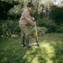 Donna che usa l'estirpatore Fiskars Ergonomic in giardino per rimuovere le erbacce.