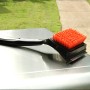 Spazzola per griglia Char-Broil Cool Clean Premium con setole e raschietto su una griglia.