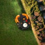Robot rasaerba Worx M800 WR308E Landroid Vision autonomo su prato vicino a un muro di pietra.