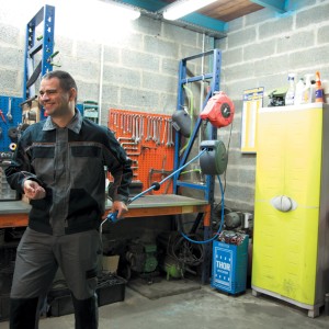 Officina con accessori per compressori e artigiano in abiti da lavoro.