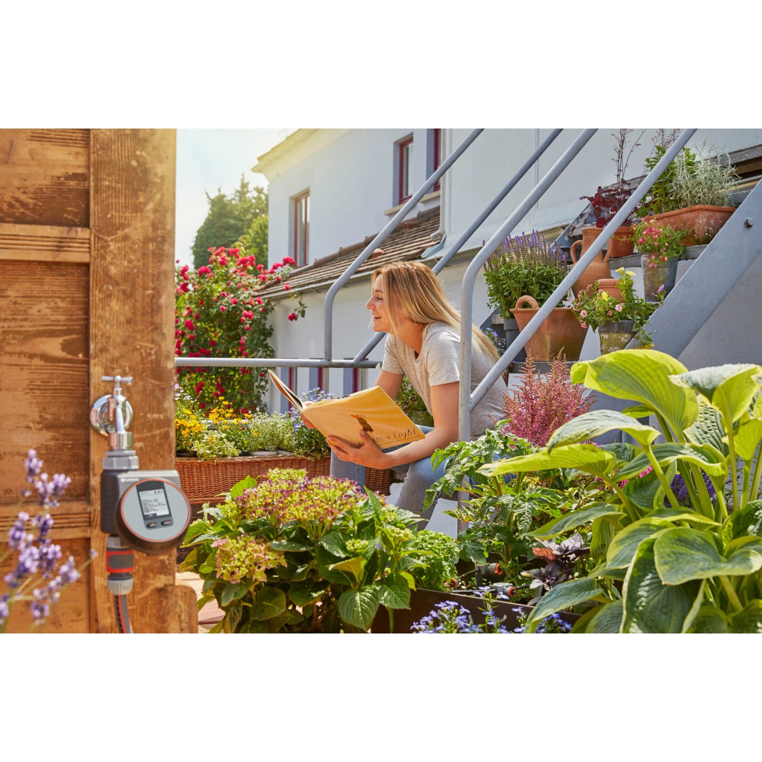 Computer per irrigazione Gardena Flex su rubinetto con donna sulle scale in giardino.
