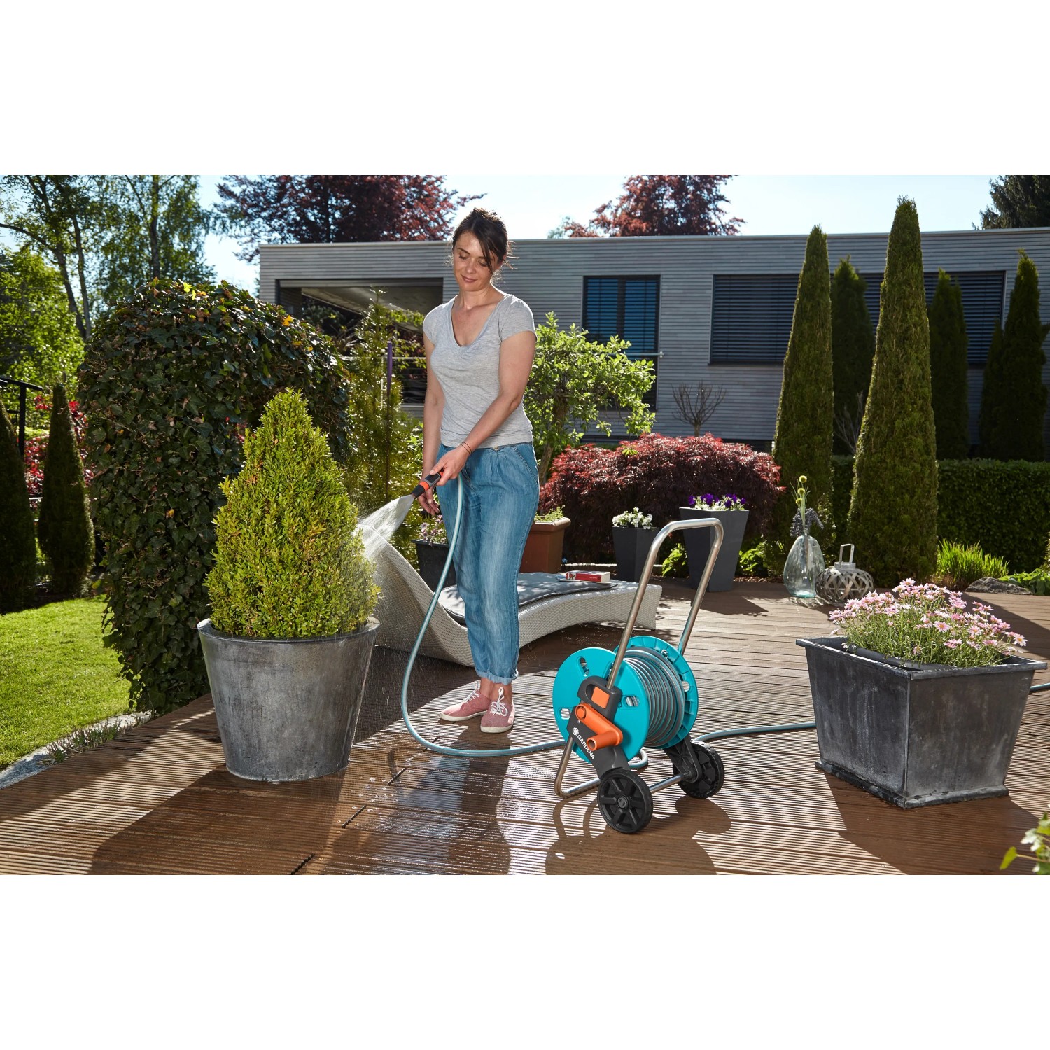 Donna che annaffia le piante con l'avvolgitubo Gardena CleverRoll S 20 m in giardino.