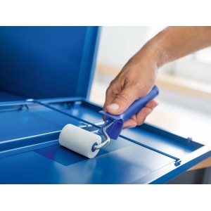 Mano che dipinge superficie blu con rullo in schiuma LUX (5 cm). Set di rulli per verniciatura fine.