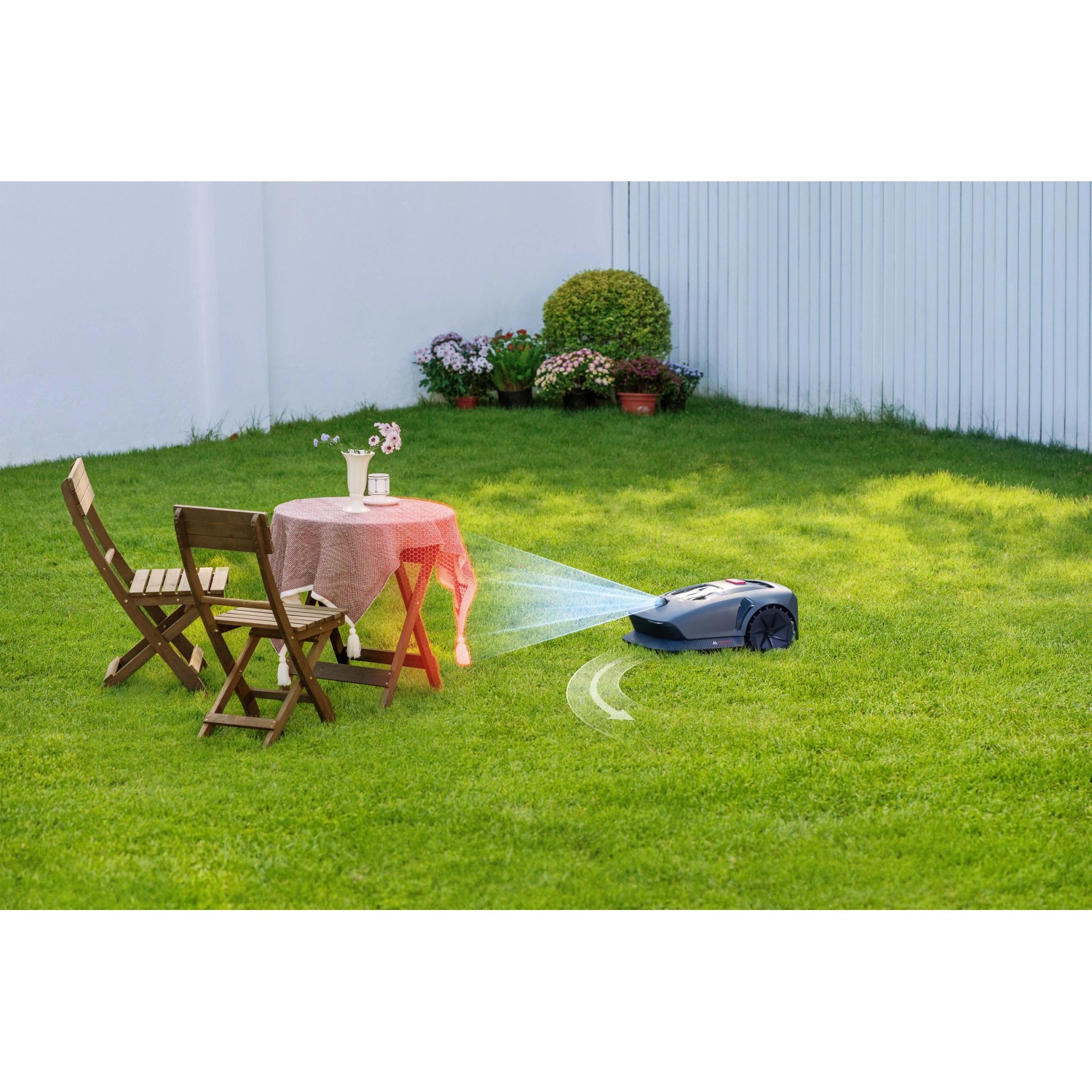 Robot tagliaerba grigio t.b.t. in azione su un prato verde in giardino.