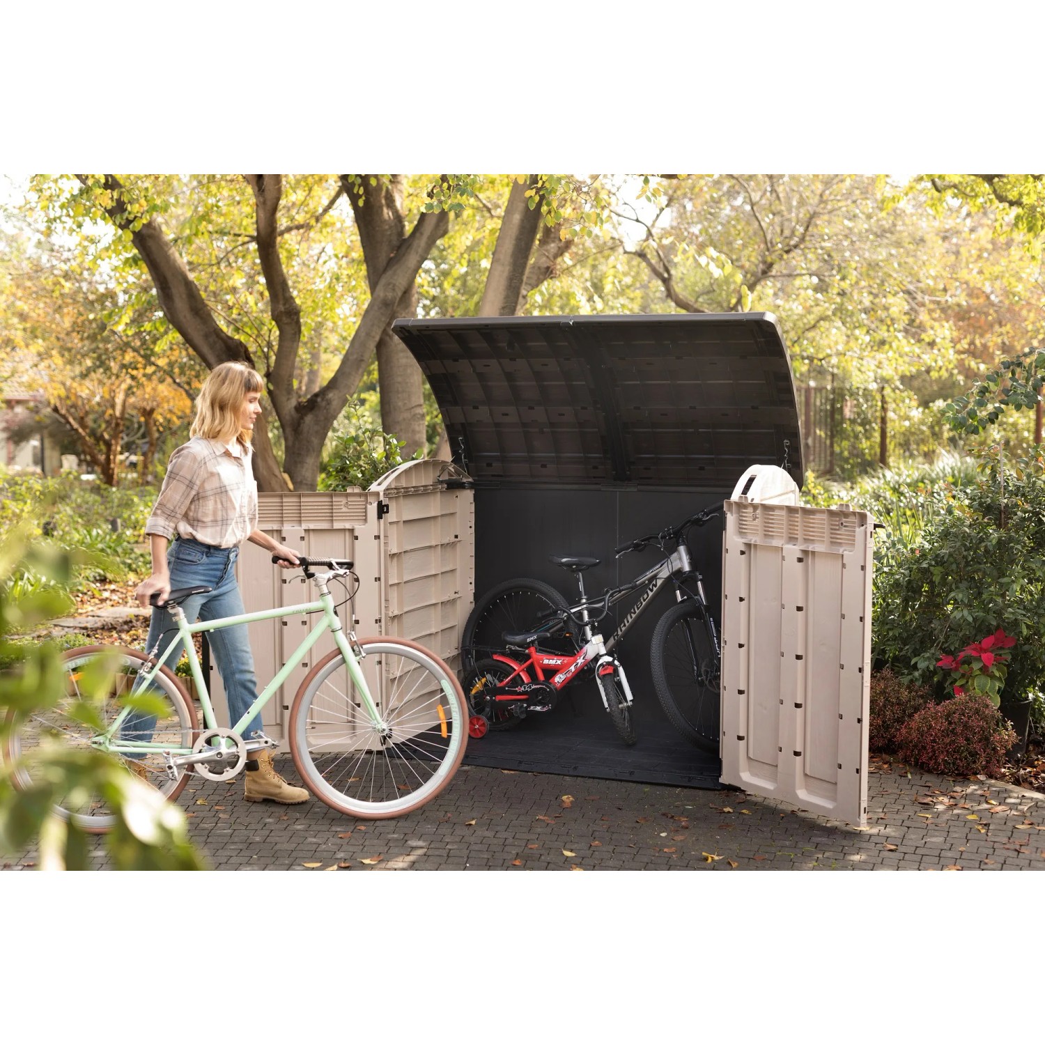 Box contenitore Keter Store It Out Ultra, beige/marrone, con biciclette e coperchio aperto.