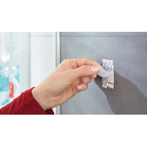 Applicazione di un gancio adesivo t.b.t. su una parete grigia.